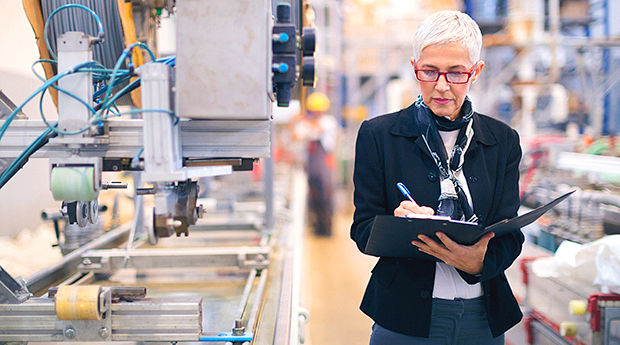 Older woman with clipboard in manufacturing warehouse